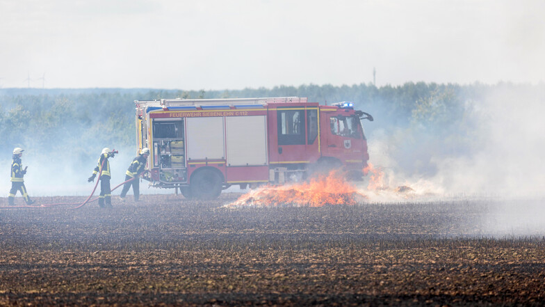 Die Feuerwehr kämpft mit Wasser gegen die Flammen auf dem Feld an. Die Flammen haben sich rasant ausgebreitet.