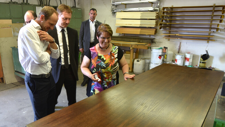 Seifhennersdorfs Bürgermeisterin Karin Berndt zeigt  Ministerpräsident Michael Kretschmer (Mitte) und CDU-Landtagsabgeordneten Stephan Meyer einen von Bechstein restaurierten historischen Tisch aus dem Rathaus.