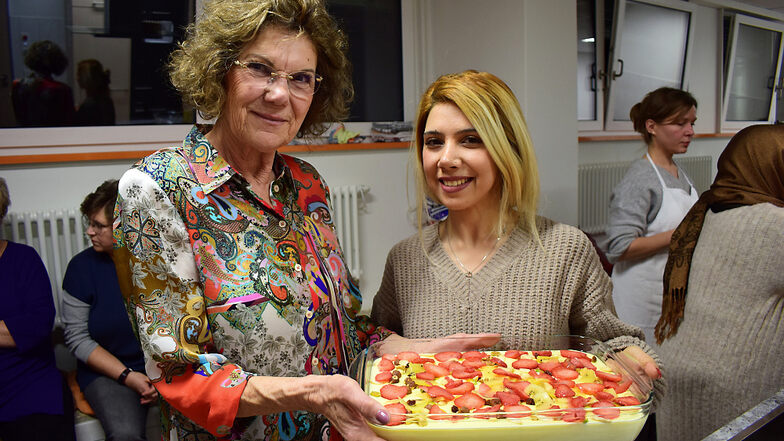 Kristina Niemz (l.) aus Bröthen hat mit ihrem Mann Dietmar den Pudding nach Najia Karimis (r.) Rezept vorbereitet. Er hat einen Kuchenboden und ist dekoriert mit frischem Obst sowie Trockenfrüchten und Nüssen.