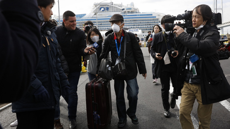 Ein Passagier wird von Journalisten empfangen, nachdem er das Kreuzfahrtschiff verlassen hat.