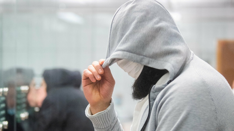 Abu Walaa, mutmaßlicher Anführer der Terrormiliz Islamischer Staat (IS) in Deutschland, steht im Oberlandesgericht hinter einer Glasscheibe.