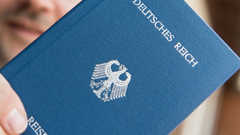 Ein Mann hält ein Heft mit dem Aufdruck "Deutsches Reich Reisepass" in der Hand.