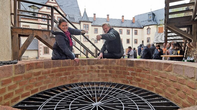 Burgchefin Susanne Tiesler und der technischer Leiter Jörg Nollau weihen den neuen, alten Burgbrunnen von Mildenstein mit einem Schluck Sekt ein.