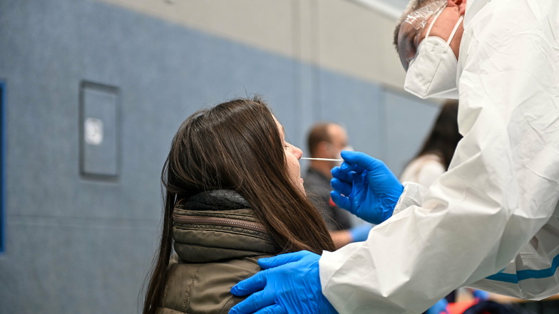 Eine junge Frau lässt sich in der Sporthalle von Räckelwitz auf das Coronavirus testen. Alle Einwohner der Gemeinde waren dazu am Freitag aufgerufen.