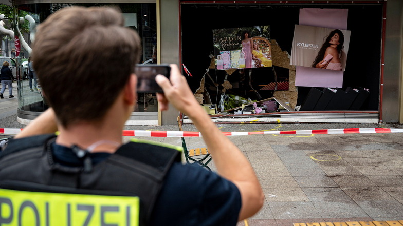 Ein Polizist fotografiert die beschädigte Ladenfront am Unfallort.