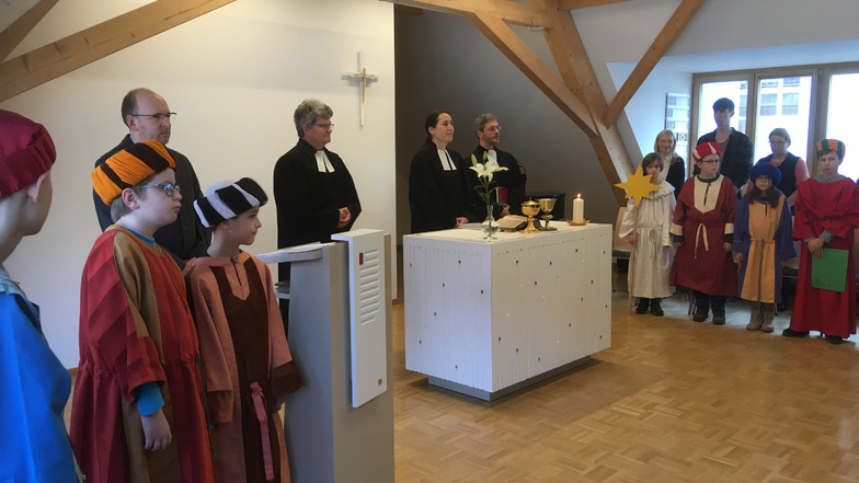 Die Pfarrer Pohl, Zehme und Adolph (Bildmitte) sowie die Sternsinger am neuen Altar im Gemeinderaum.
