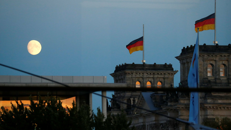Der Mond ist am Himmel über dem Reichstagsgebäude in Berlin zu sehen, dem Sitz des Bundestages. Die neuen Corona-Maßnahmen von Bund und Ländern stoßen auf Kritik.