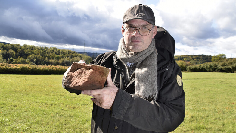 Archäologe Thomas Westphalen zeigt auf dem früheren Coschützer Burggelände einen Sandstein, der noch rötliche Spuren eines früheren Brandes aufweist.