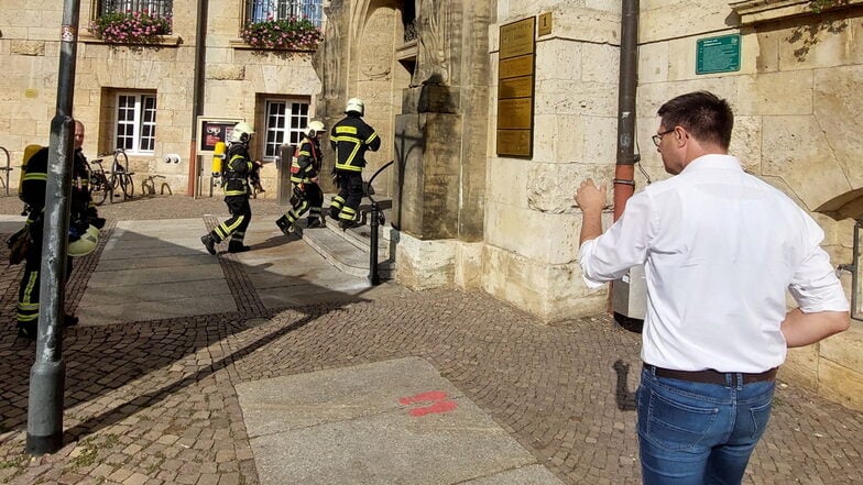 Feuerwehrleute betreten das Döbelner Rathaus, um es nach einem Feueralarm zu durchsuchen. Oberbürgermeister Sven Liebhauser spricht mit ihnen.