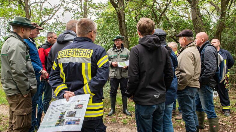 Revierförster Gunter Schwarz (Mitte) und Feuerwehrleute aus Röderaue erklären beim Infotag, wie der Brandschutz im Forst gewährleistet werden kann.