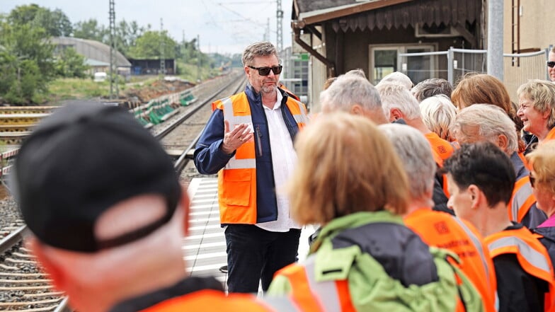 Bauleiter Jörg Seebach besichtigt mit einer Besuchergruppe den neu gestalteten Bahnsteig am Glaubitzer Bahnhofsgebäude, das im März 2025 abgerissen werden soll.