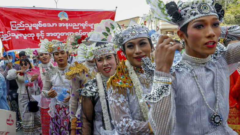 Demonstranten, geschminkt und gekleidet in traditionellen Tanzkostümen, marschieren gegen den Militärputsch.