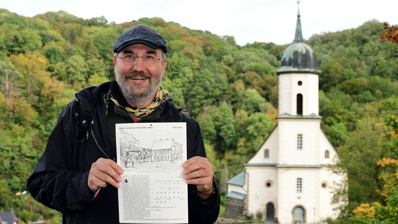 Kai Tempel steht mit seinem neuen Kalender „Dörfer am und im Tharandter Wald“ auf der Burgruine Tharandt mit der Kirche im Hintergrund. Beides Motive, die er auch gezeichnet hat.