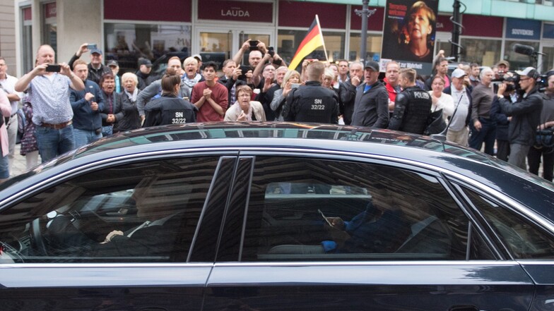 Bundeskanzlerin Angela Merkel verlässt in ihrem Dienstwagen vor Demonstranten das Albertinum in Dresden.