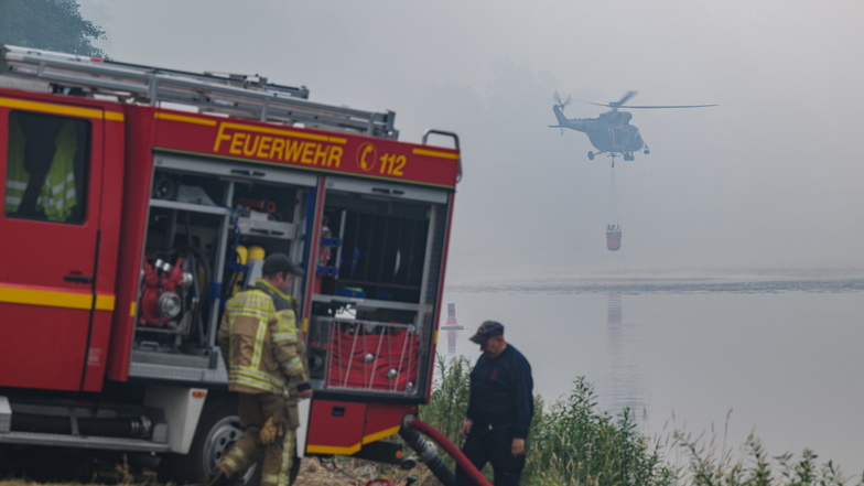 Ein tschechischer Militärhubschrauber holt bei Schmilka Wasser aus der Elbe, während deutsche Feuerwehrleute an der Löschwasserversorgung beim Kampf gegen die Waldbrände in der Sächsischen Schweiz arbeiten.