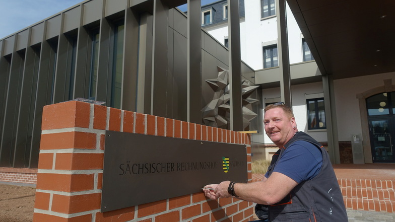 Jens Stein von der Firma Werbetechnik Leipzig bringt ein neues Schild am Landesrechnungshof in Döbeln an.