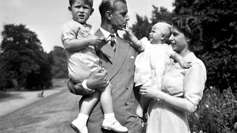 1951, Prinzessin Elizabeth (r), die Prinzessin Anne in den Armen hält, und Prinz Philip, der Prinz Charles trägt, stehen auf dem Gelände von Clarence House.