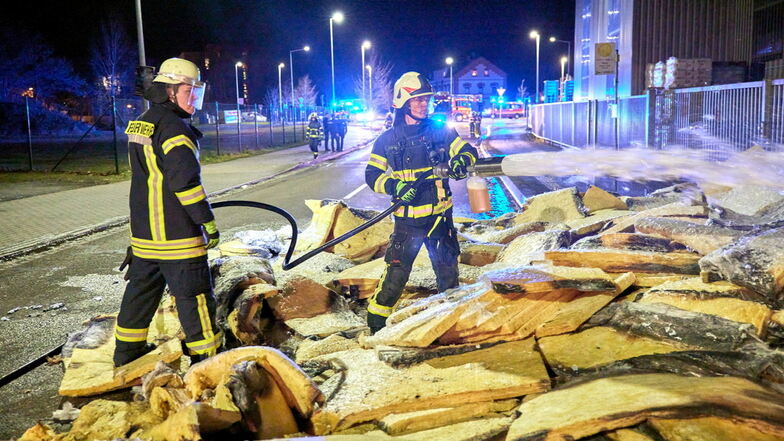 Brand im Pirnaer Baumarkt: Feuerwehrleute löschen die Dämmwolle auf der Straße.