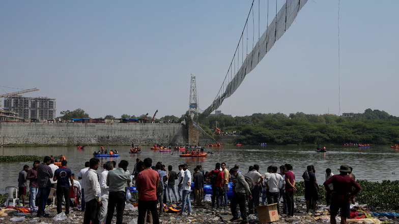Einsatzkräfte auf Booten suchen im Fluss Machchu nach dem Einsturz einer Hängebrücke im indischen Morbi nach weiteren Opfern.
