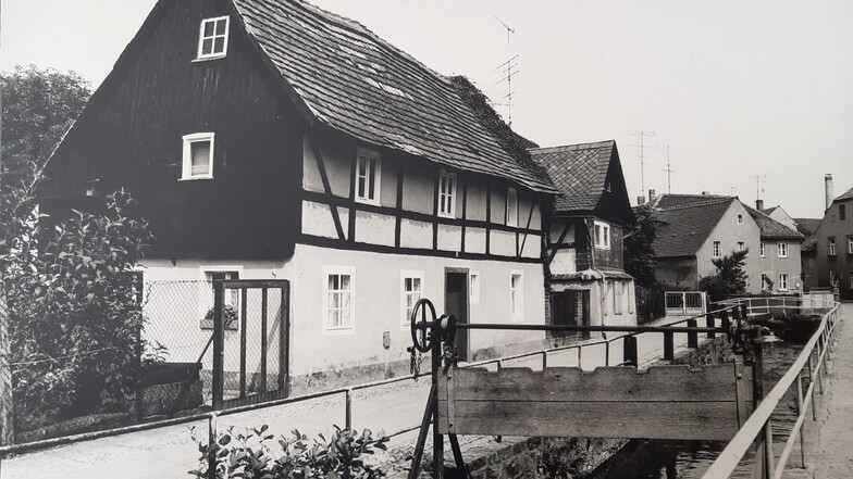 An den Häusern der Uferstraße führte bis Ende der 1990er-Jahre noch das alte Flussbett der Schwarzen Elster vorbei, ehe es verlegt wurde. Auf dem Bild aus DDR-Zeiten sieht man noch das alte Wehr.