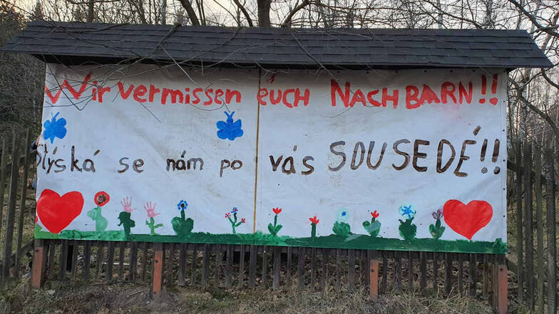 "Wir vermissen euch Nachbarn" steht auf einem Leinentuch, das beim Oybiner Ortsteil Hain auf tschechischer Seite an einem Zaun hängt.