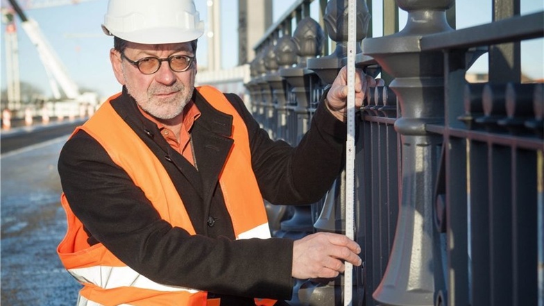 Straßenbauamtschef Reinhard Koettnitz demonstriert mit dem Zollstock, dass das nachgebaute historische Geländer nicht die nötige Höhe erreicht.