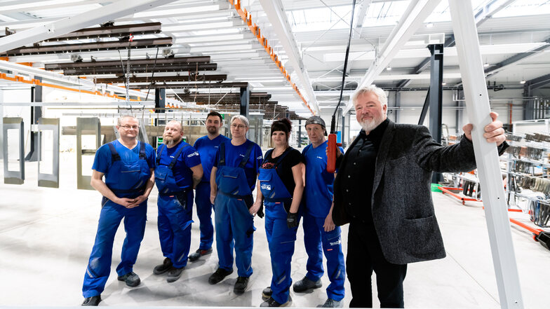 Bei Käppler & Pausch ist man stolz auf die neue Farbgebung – das Foto zeigt den Geschäftsführer Klaus Gerlach und einige Mitarbeiter. Die Logistik in der Halle läuft über ein oberirdisches Schienensystem. Mittels Knopfdruck lassen sich darauf auch schwere