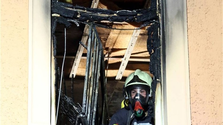 Ein Feuerwehrmann schaut aus dem ausgebrannten Zimmer.