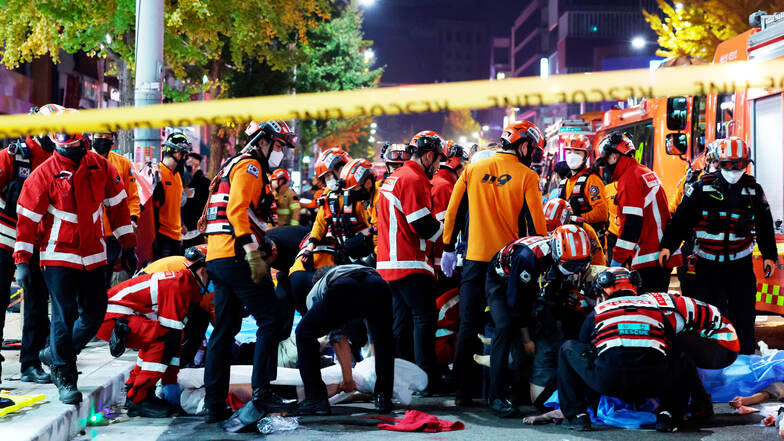 Rettungskräfte und Feuerwehrleute sind an der Unfallstelle im Einsatz. Dutzende Personen haben beim Ansturm auf Halloween-Feierlichkeiten in Seoul einen Herzstillstand erlitten.