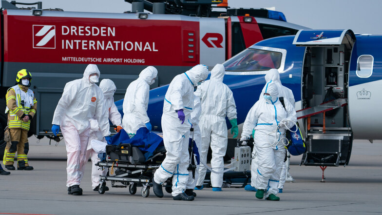 Ein französischer Corona-Patient wird von medizinischen Fachkräften auf dem Flughafen Dresden in einen Intensiv-Krankenwagen überführt. Insgesamt sind am Samstag bislang zwei Covid19-Patienten aus Frankreich auf dem Flughafen Dresden gelandet.