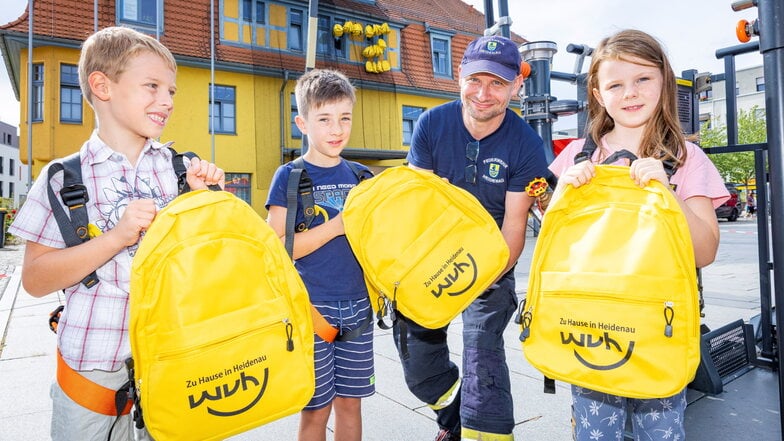 Anton, Elias und Lea (v.l.n.r.) pflückten sich sich bei der ABC-Fete in Heidenau gefüllte Rucksäcke von Stadthaus. Michael Haßbacher von der Freiwillige Feuerwehr half ihnen dabei.