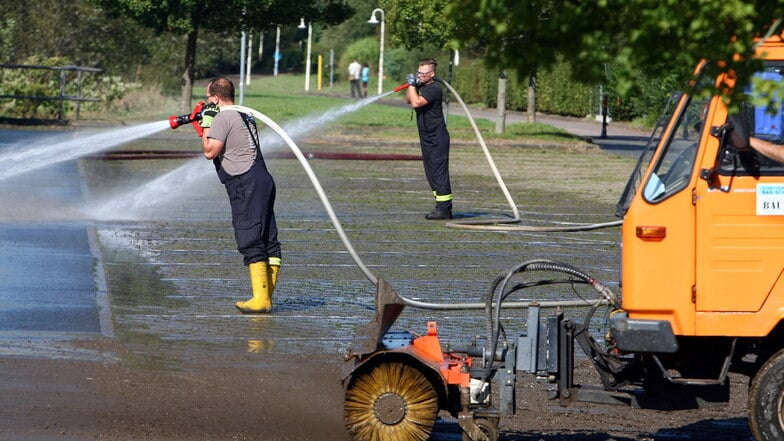 Feuerwehr und Bauhof reinigen den Parkplatz am Elbkai in Bad Schandau.