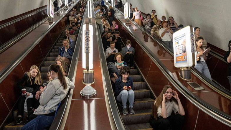 Menschen sitzen in Kiew auf einer Rolltreppe, während sie in einer Metrostation Schutz vor Raketenangriffen suchen.