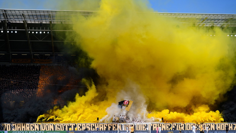 Eine weitere Choreografie der Dresdner Fans. In schwarzen, weißen und gelben Regenponchos stellen sich die Fans auf, dazu wird Pyrotechnik gezündet.