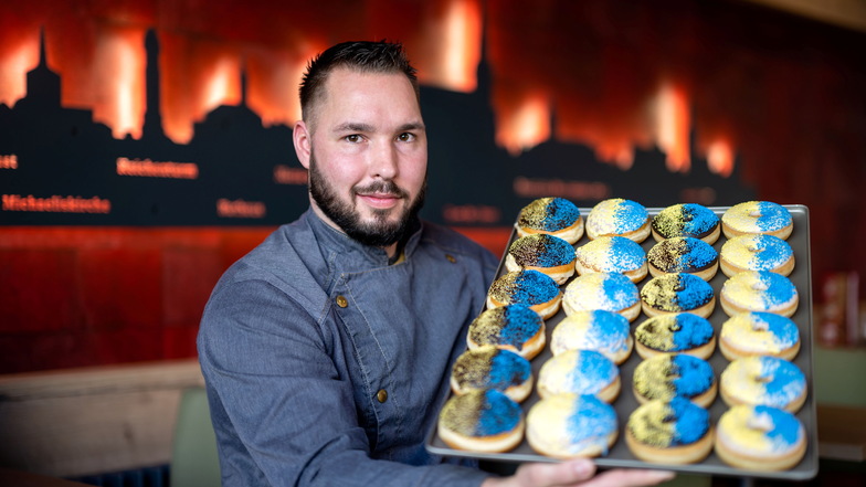 Blau-gelb verzierte Donuts und Pfannkuchen werden ab Donnerstag beim Bäcker Jeremias verkauft. Das erste Blech, das Betriebsleiter Martin Reck hier zeigt, ging bereits am Dienstag über die Ladentheke. Den Erlös spendet die Bäckerei in die Ukraine.