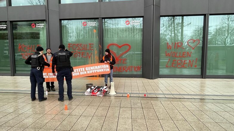 Mitglieder der Bewegung "Letzte Generation" kippen Farbe auf den Hauptsitz der SachsenEnergie nahe dem Hauptbahnhof. Die Polizei nimmt die Personalien auf.