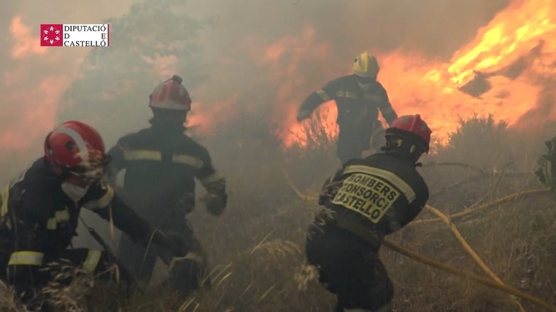 Feuerwehrleute laufen bei Löscharbeiten eines Waldbrandes in Bejís vor den Flammen davon. Dort, in der Region Valencia, gab es beim Stopp eines Zuges in den Flammen Verletzte.