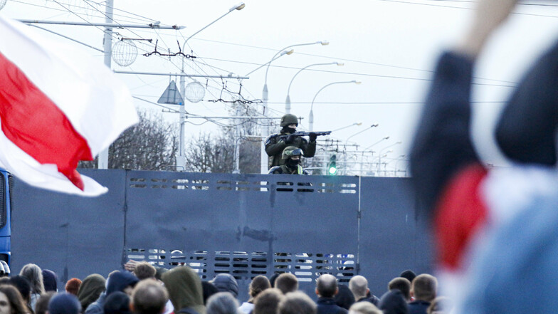 Bewaffnete belarussische Polizeibeamte bewachen während eines Protests in Minsk eine Straßensperre hoch über den Demonstranten.