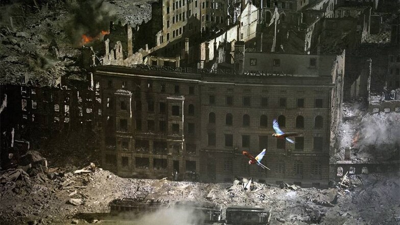 In einem Detail des riesigen Bildes fliegen aus Käfigen entkommene Papageien zwischen den Ruinen der Stadt.