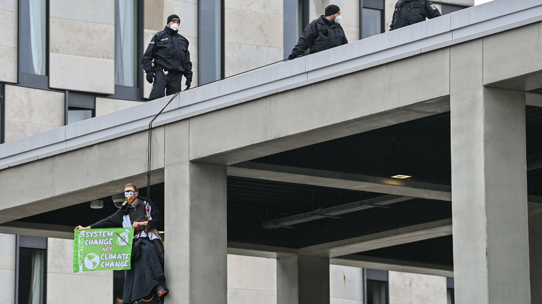 Ein Klima-Aktivist hängt mit einem Transparent an einer Fassade vom Terminal 1.