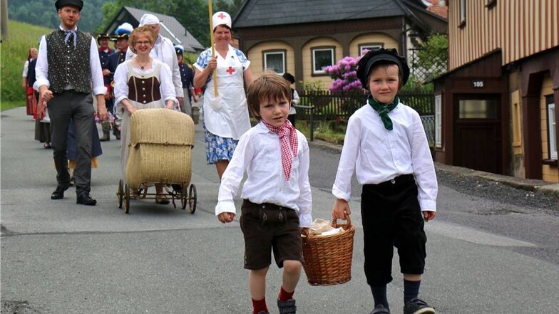 Die Teilnehmer des Volkskunde- und Mühlenmuseums Waltersdorf laufen im Festumzug in original Oberlausitzer Trachten.