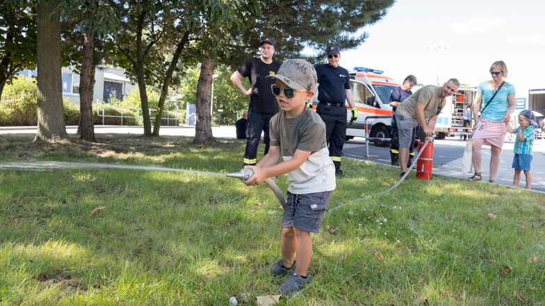 Ein kleiner Feuerwehrmann: Robin mit Feuerwehrschlauch, Vater Martin Heinrich pumpt im Hintergrund.