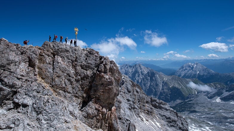 Bergsteiger am Gipfelkreuz der Zugspitze: Ein Bergsteiger ist an der Zugspitze in die Tiefe gestürzt und gestorben (Archivbild).