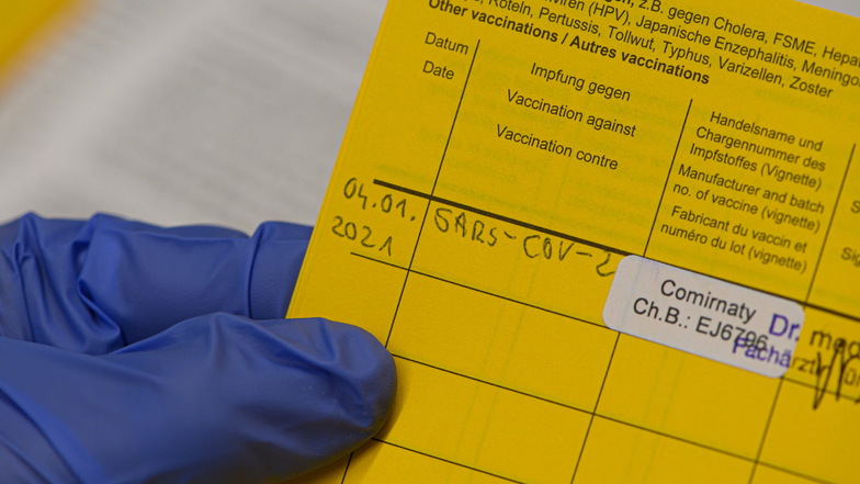 Eine Mitarbeiterin im Städtischen Klinikum Dresden trägt in einem Impfausweis die Impfung gegen Corona ein. In Deutschland haben Geimpfte bisher keinen Vorteil gegenüber Ungeimpften.