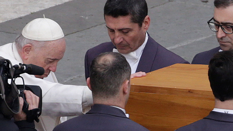 Papst Franziskus (l) berührt den Sarg, bevor die Sargträger den Sarg des verstorbenen emeritierten Papstes Benedikt XVI. nach der öffentlichen Trauermesse auf den Petersplatz wegtragen.