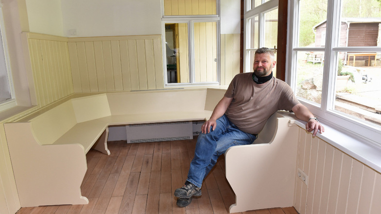 Dirk Hahmann sitzt auf einer neu gebauten Bank im früheren Eingangsbereich der Veranda.