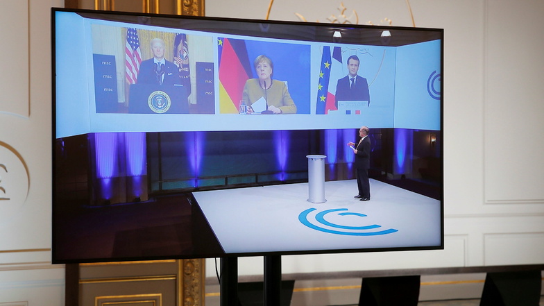 Joe Biden (l), Präsident der USA, Bundeskanzlerin Angela Merkel (M) und Emmanuel Macron, Präsident von Frankreich, sind auf einem Bildschirm im Elysee-Palast während ihrer Teilnahme an der virtuellen Münchner Sicherheitskonferenz eingeblendet.