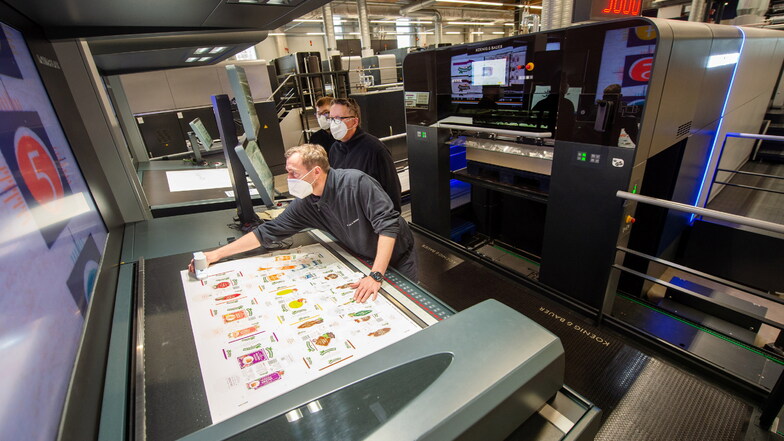 Die Druckinstrukteure Bjoern Sagasser (r.)und Ralf Maskos sind mit Azubi Martin Weser (hinten) an der Druckmaschine Rapida 106x mit der Farbabstimmung beschäftigt. Knapp 1.700 Beschäftigte arbeiten bei Planeta Radebeul. Es gibt viele freie Stellen.