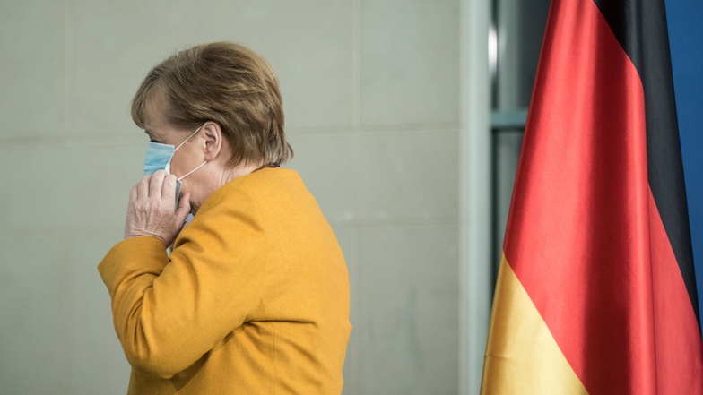 Bundeskanzlerin Angela Merkel (CDU) setzt ihre Maske auf und geht nach ihrem Statemant weg.