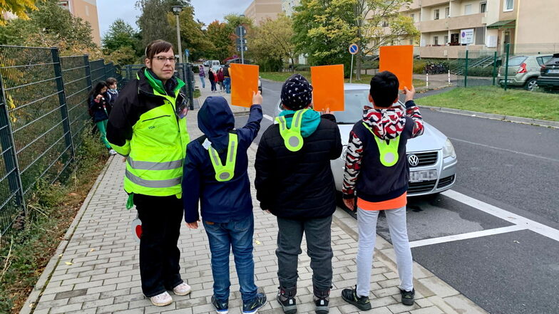 Leon, Tim und Omar zeigen die Rote Karte. Ein Auto steht im Parkverbot, direkt vor der Curie-Grundschule.
